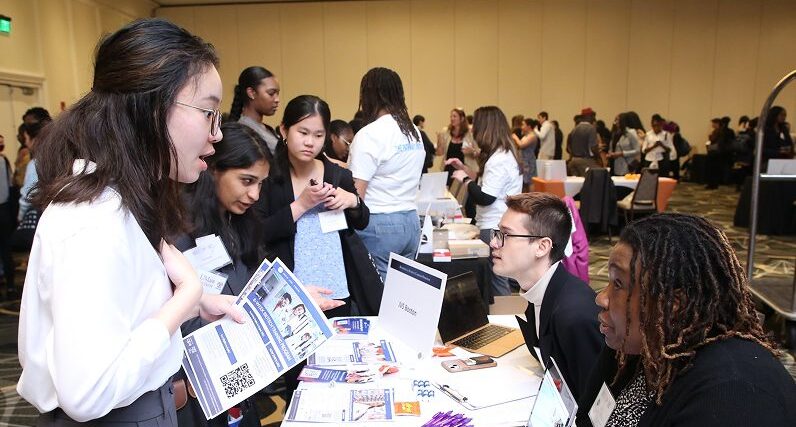 female student talking with company representative at informational table