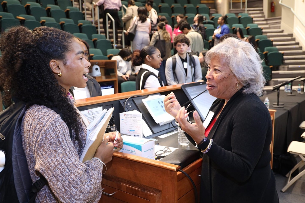 Student and instructor talking near podium in classroom