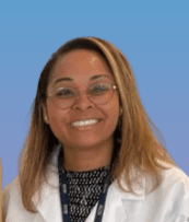 Victoriana Schwartz, MD, MPH in a white doctor coat smiling at camera