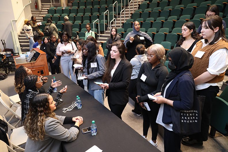 students in front of panel of speakers after lecture