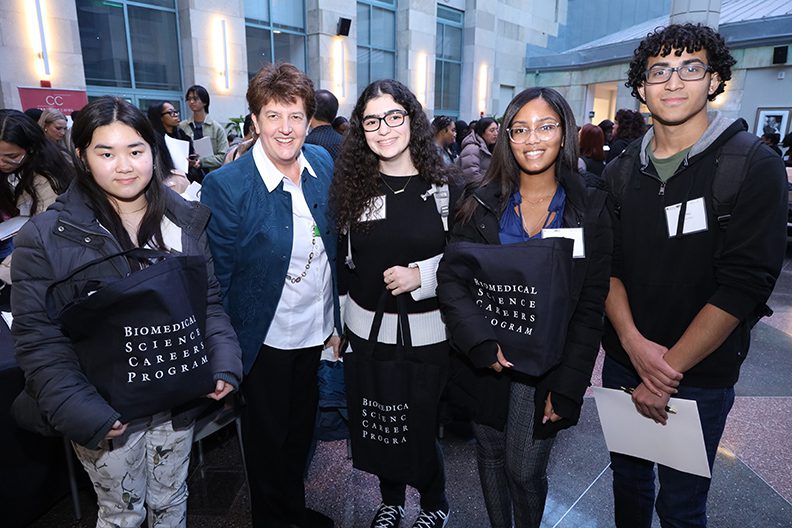 students and advisor in row smiling at camera