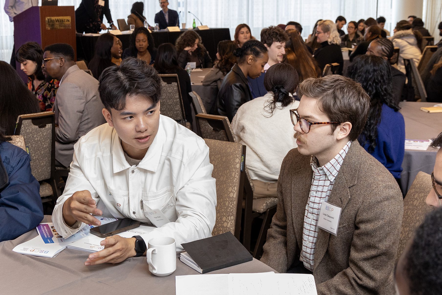 two men sitting at table talking to each other