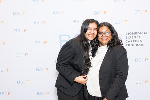 two women standing in front of bscp step and repeat smiling