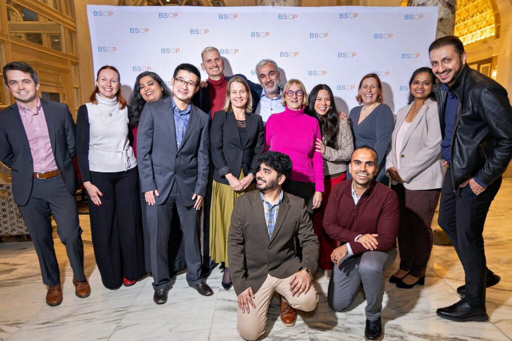 representatives from corporate partner pose together in front of BSCP step and repeat display smiling