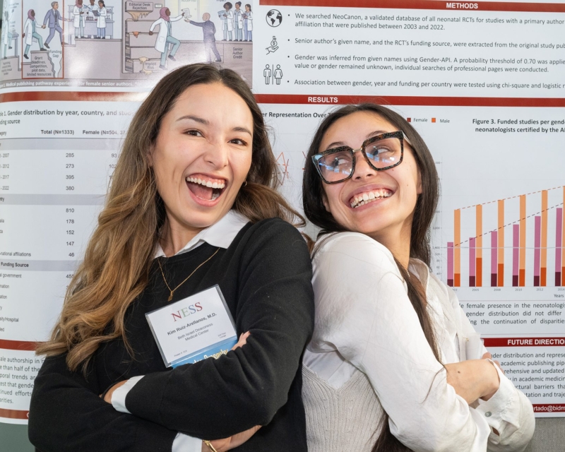 two women back to back in front of poster presentation smiling