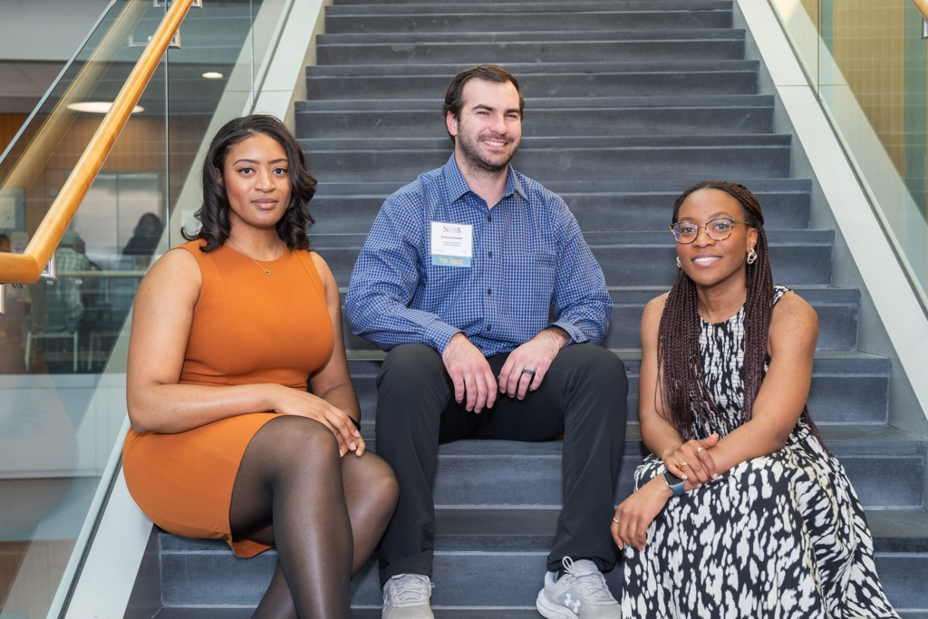 woman, man and woman sitting on stairs looking at camera smiling