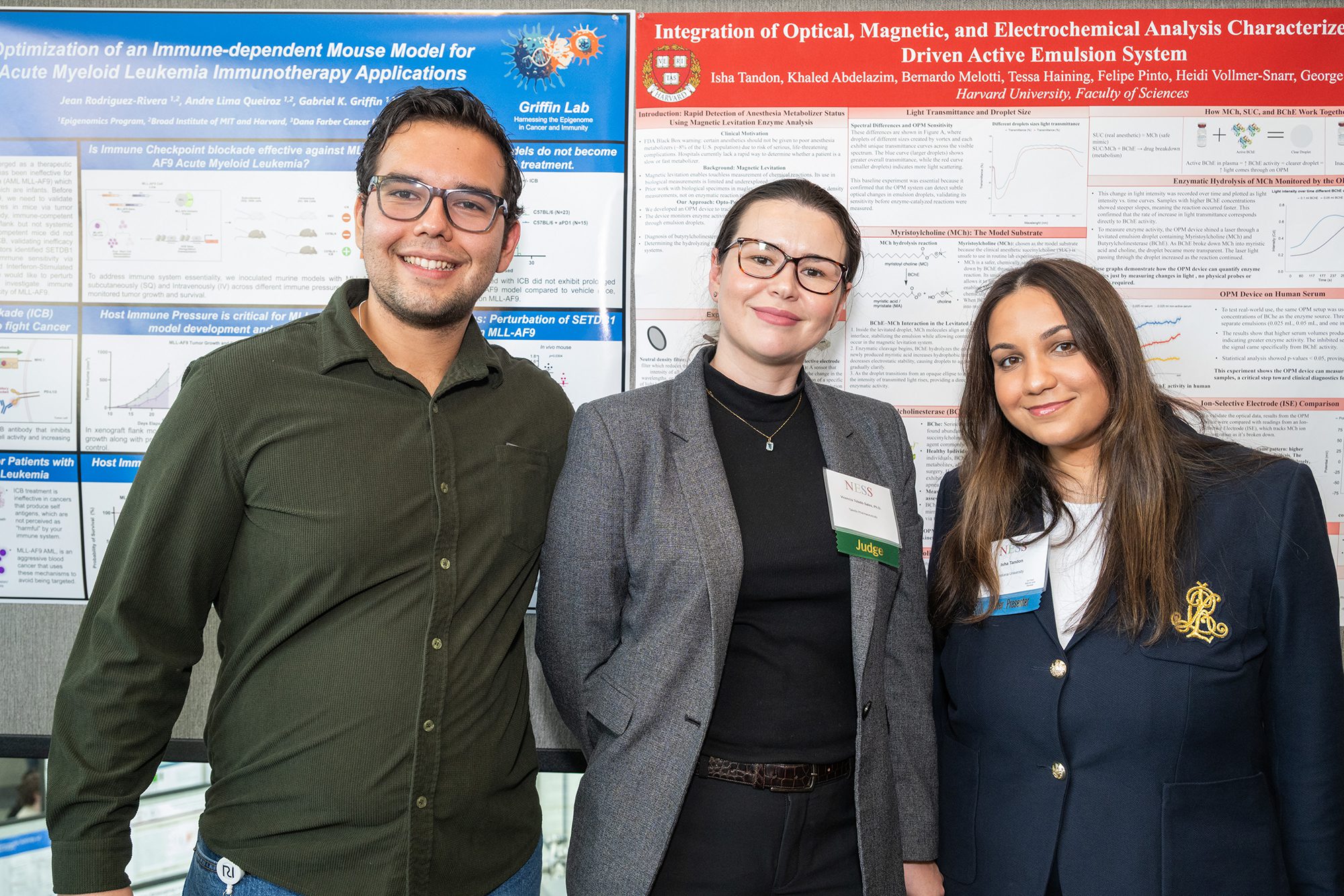 man and two women standing shoulder to shoulder in front of presentations smiling at camera