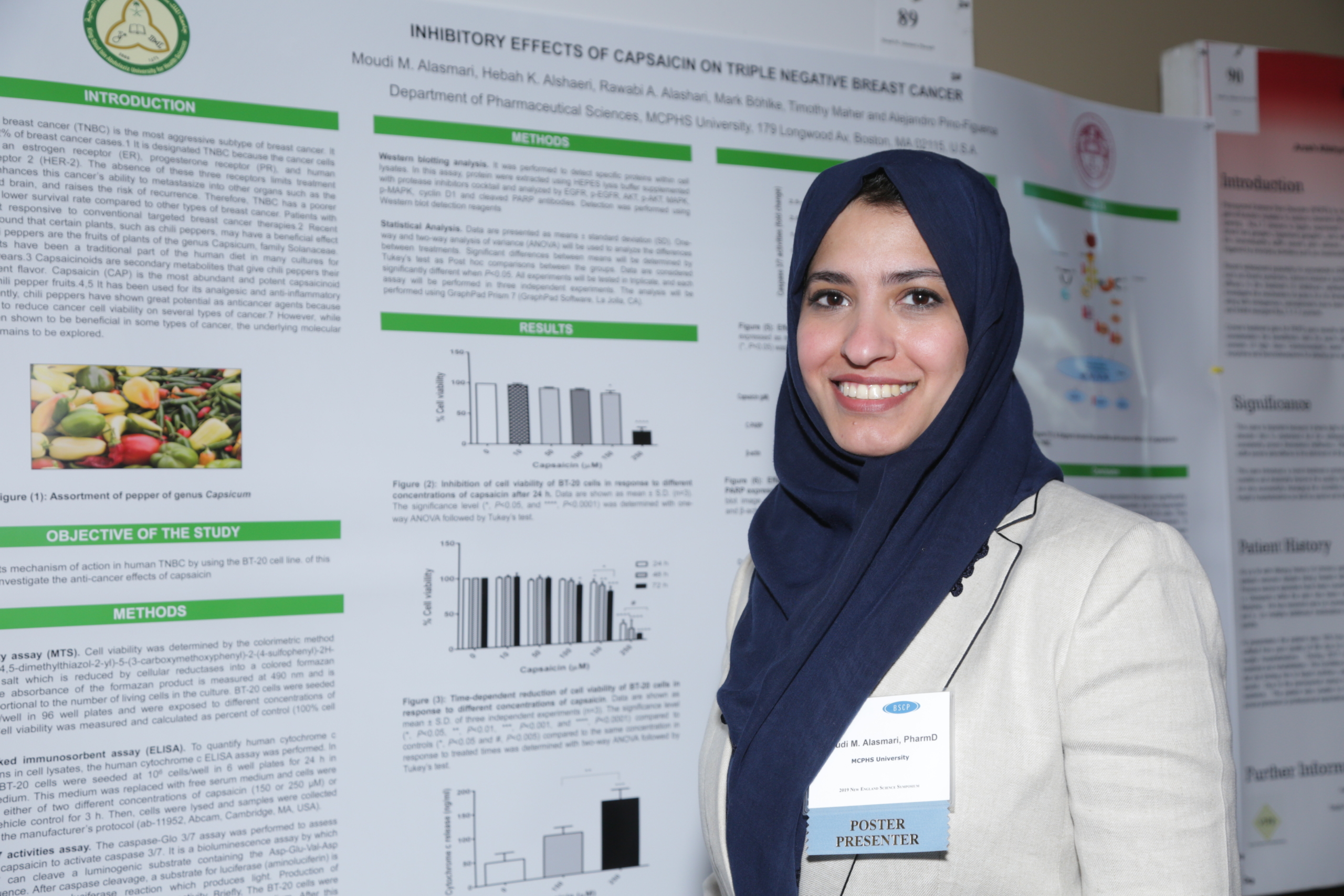 student researcher poses in front of poster presentation